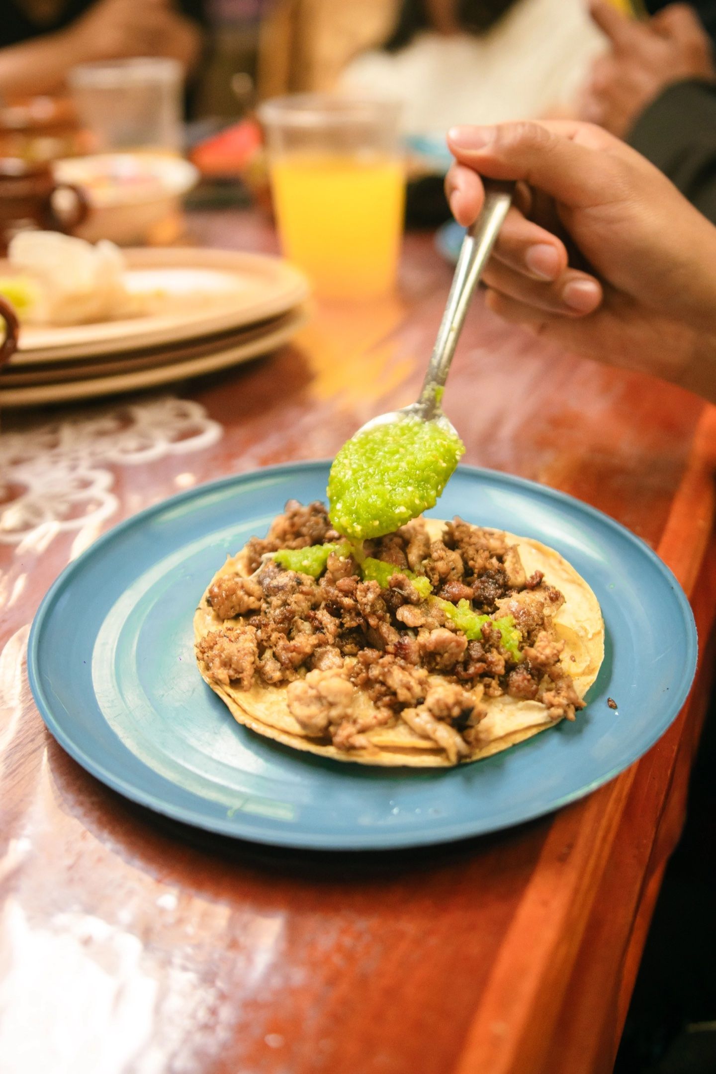 Tacos garnis de viande hachée et de sauce verte, sur une assiette bleue